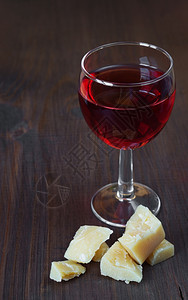 一杯红葡萄酒和黑木板上一块干酪图片