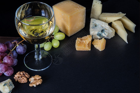 白葡萄酒各种类的奶酪胡桃和黑底葡萄图片
