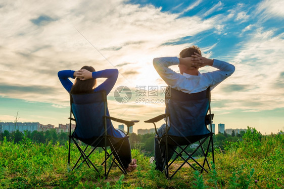 男人和女坐在椅子上仰慕城市的日出图片