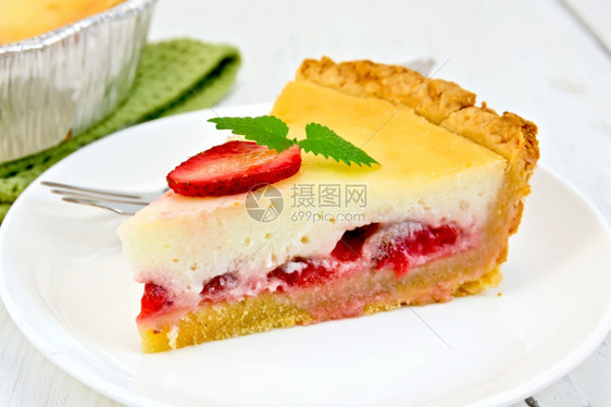 一份草莓派上面有奶油酱叉子草莓白板薄荷餐巾纸和面粉以及背景浅木板上的馅饼图片