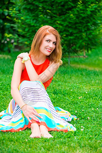 穿着裙子的女孩坐在绿草坪上图片