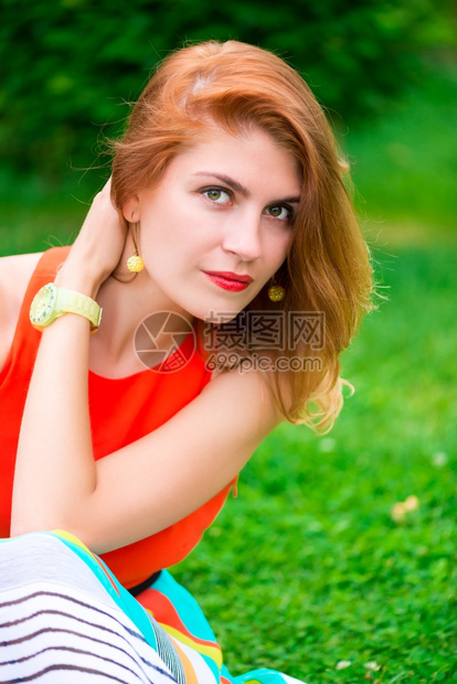 一位坐在公园草地上的漂亮女孩肖像图片
