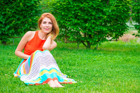 穿着裙子的女人坐在绿草坪上图片
