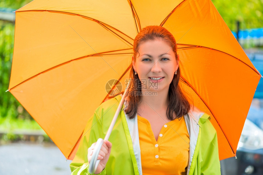 一个年轻棕发美女的肖像和橙色雨伞贴近图片