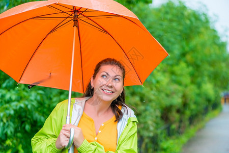 穿着雨衣在中的橙色伞下图片
