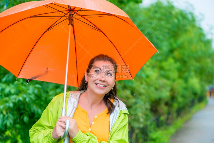 穿着雨衣在中的橙色伞下图片