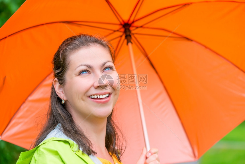 带着橙色雨伞走在中笑着的漂亮女孩图片