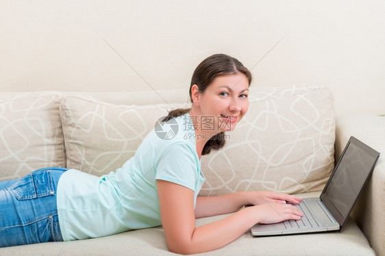 女人躺在沙发上用笔记本电脑图片