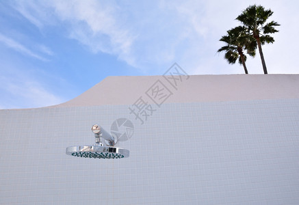 悬挂在白色玻璃板砖墙上的金属淋浴紧闭式金属淋浴复制空间图片