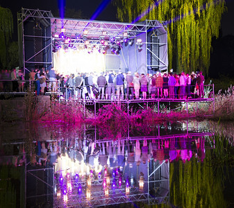 人们在夜间的音乐会上在水中反射出来图片
