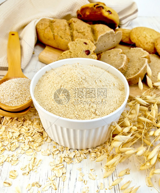 白碗中的面粉勺子燕麦和茎面包木板底的饼干图片