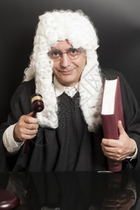 男律师的肖像持有法官大锤和黑背景书籍的男律师图片