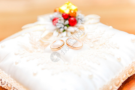 一对金色的结婚戒指放在一个漂亮的枕头上特写图片