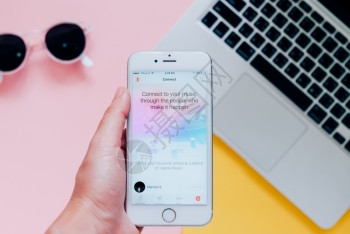 2016年月8日手持苹果iphone6显示苹果音乐应用程序并带有笔记本电脑背景苹果音乐是新推出的ibones音乐流服务图片