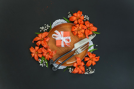 带有橙丽花和礼品盒的衣板装饰着橙色百丽花和礼品盒的衣板上面绑有白带丝和黑色桌上的独家伪造餐具顶楼平面背景图片