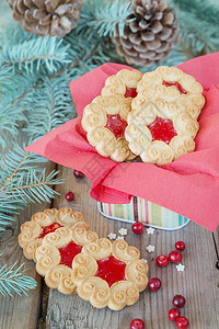圣诞桌甜饼干在旧木桌上加果酱红莓鲜树枝和锥形甜饼图片