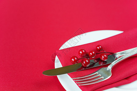 白瓷板上有刀和叉子红色纸巾薄和胡椒浆白瓷板位于一张上面有红色桌布的子上有文字空间图片