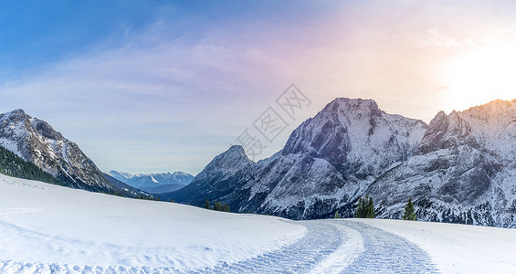 高山全景带雪路冬季风景由雪车铺设的一条路在12月的阳光明媚一天在奥斯特里亚高山上的雪层中留下痕迹图片