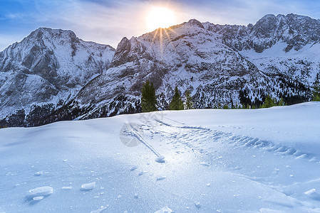 雪山和牧场上的冰壳冬季明亮的一天高山风景冰壳上的细节位于奥斯特里亚山的牧场表面由于太阳的温暖从岩石峰后面发光图片