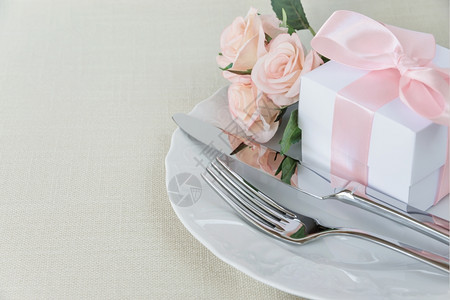 漂亮的装饰桌有白色板礼品盒有粉色丝带餐具和粉红色花在桌布上有文字空间图片