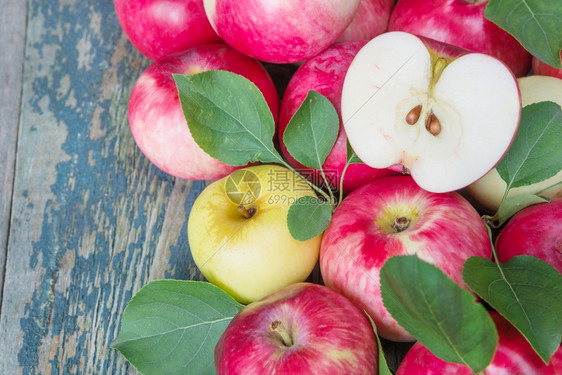 有很多红苹果旧木制桌上有绿叶子的红苹果图片