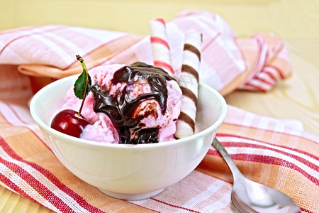 碗里的冰淇淋樱桃巧克力糖浆木板底的面包卷图片