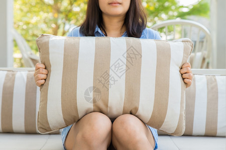 笑的年轻女人坐在椅子上抱枕头图片