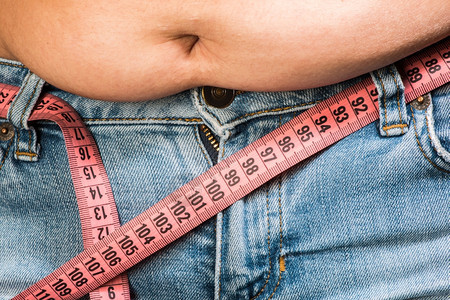 粉红色胶带测量胖肚子女人的腰围背景图片