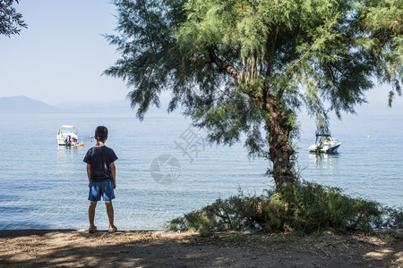 海滩上的孩子看着海和船图片