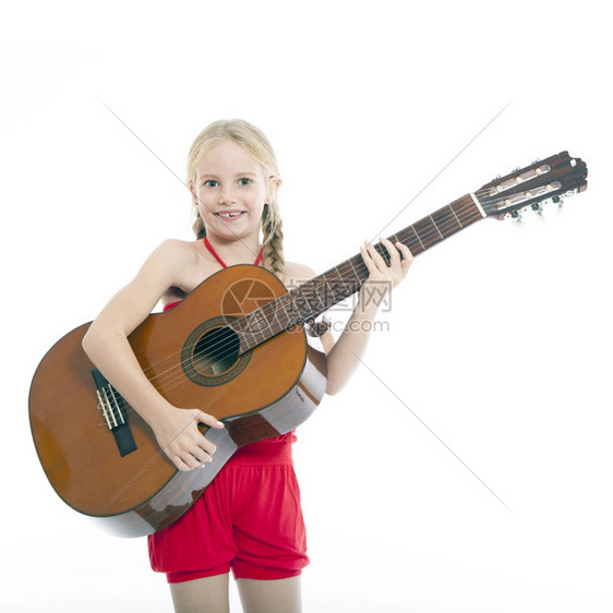 年轻女孩在白色背景下学习弹吉他图片