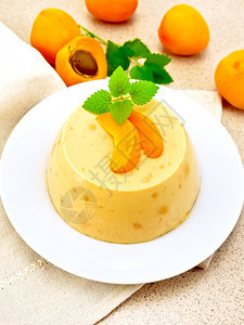 甜点椰子芝士蛋糕白盘里有杏子棕花岗岩桌背景上的餐巾纸薄荷图片