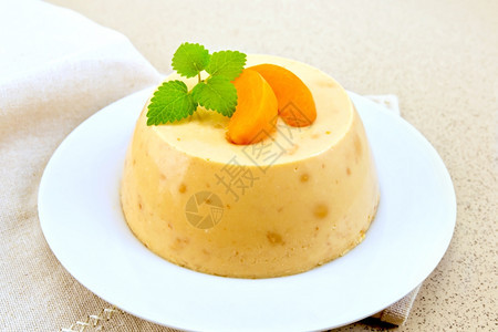 甜点pancot芝士蛋糕和白盘中的杏子在花岗岩桌背景上的餐巾纸图片