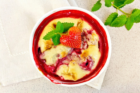 草莓布丁碗里有浆果和薄荷餐巾纸上有浆果和薄荷背景是花岗岩桌顶图片