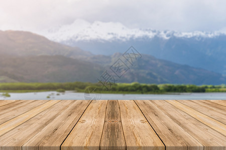 在模糊背景面前的木板空桌在森林山底的模糊湖面上看到褐色木板可以模拟显示或调换产品图片