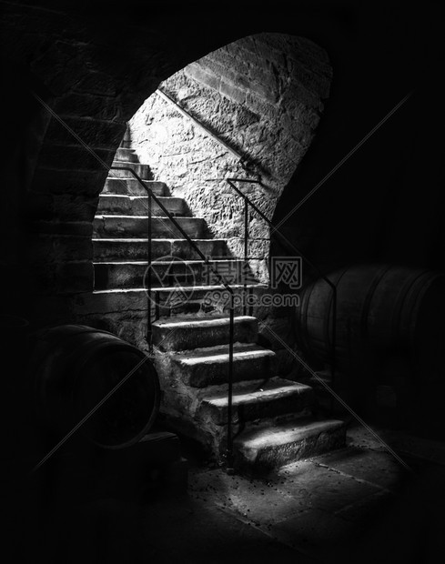 古老的石头楼梯进入废弃的酒窖黑暗阴影和小光束图片