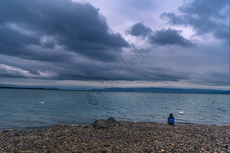 在暴风雨下的云层一个坐在河岸上思考着图片