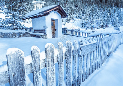 冰冻的木栅栏和土生长的礼拜堂冬季的堤坝风景上面有雪覆盖的旧木栅栏它环绕着奥斯特里亚山丘上的一座土生长高山礼拜堂照片以奥斯特里亚河图片