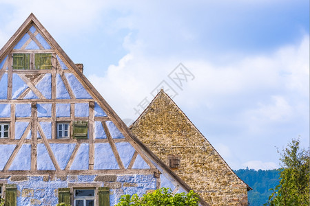两栋中世纪德国人房屋的建筑细节一栋有蓝色半木墙小窗户百叶另一栋有古老的石墙和一扇单的木窗图片