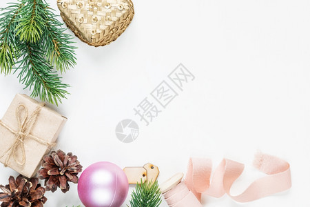 圣诞节框架由以下组成fir树枝锥形礼品箱圣诞舞会和白背景的粉色丝带有文字空间贺卡网站社交媒体杂志博客艺术家等的固定构成图片