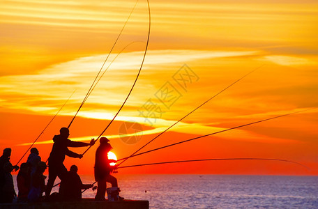 日落时在码头的渔民群体图片