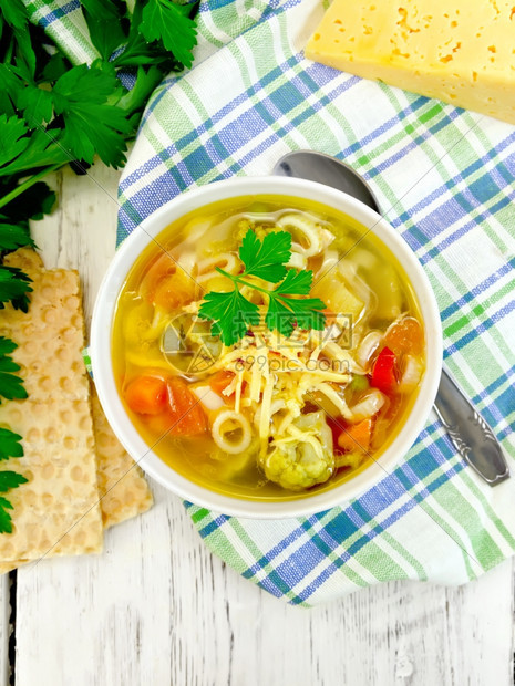 含肉菜西红柿锌和卷心菜青豆胡萝卜和意大利面在餐巾纸上碗里喷洒的干酪顶木板底的面包图片