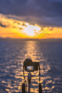 在三脚架上用dslr摄像头拍的多彩图像以活视模式在水面上捕捉美丽的日落图片