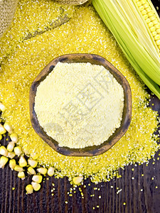 面粉玉米放在一个粘土碗里上面有粗面粉玉米棒子和谷物在上面的木板背景上放一个袋子图片