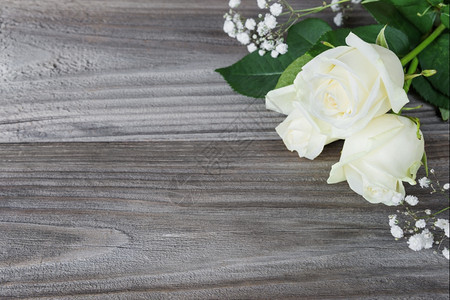 白色玫瑰花束躺在旧木板的灰色背景上为文字留出空间图片
