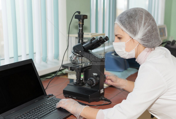 在实验室用现代电子显微镜探索生物样本的女科学家图片