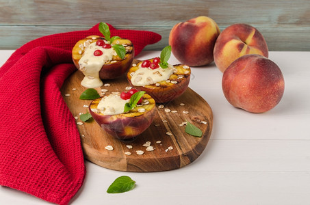 木制桌上加酸奶鹅莓和薄荷叶的烤桃子图片