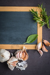 您文字的黑板石桌上的新鲜园艺草药和大蒜烹饪原料带有复制空间的顶部视图图片