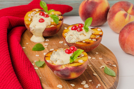 木制桌上加酸奶鹅莓和薄荷叶的烤桃子图片