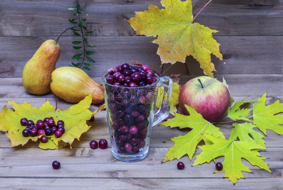 落秋叶的玻璃杯洒在红莓苹果和梨子上图片