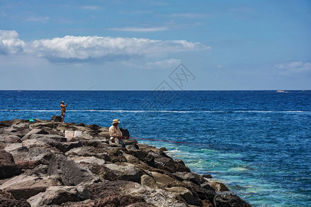 天空之鱼素材特纳里夫西班牙09126在平坦的海岸上两个人用渔棍钓鱼背景